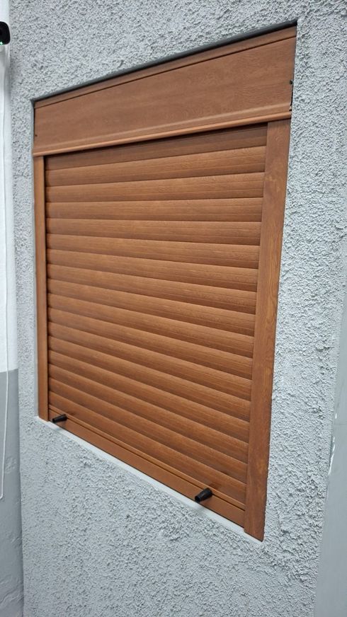 Una persiana enrollable gris instalada en una ventana de una sala de estar luminosa y moderna