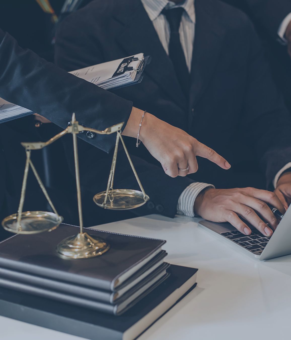 a man is typing on a laptop next to a scale of justice representing Criminal Defense.