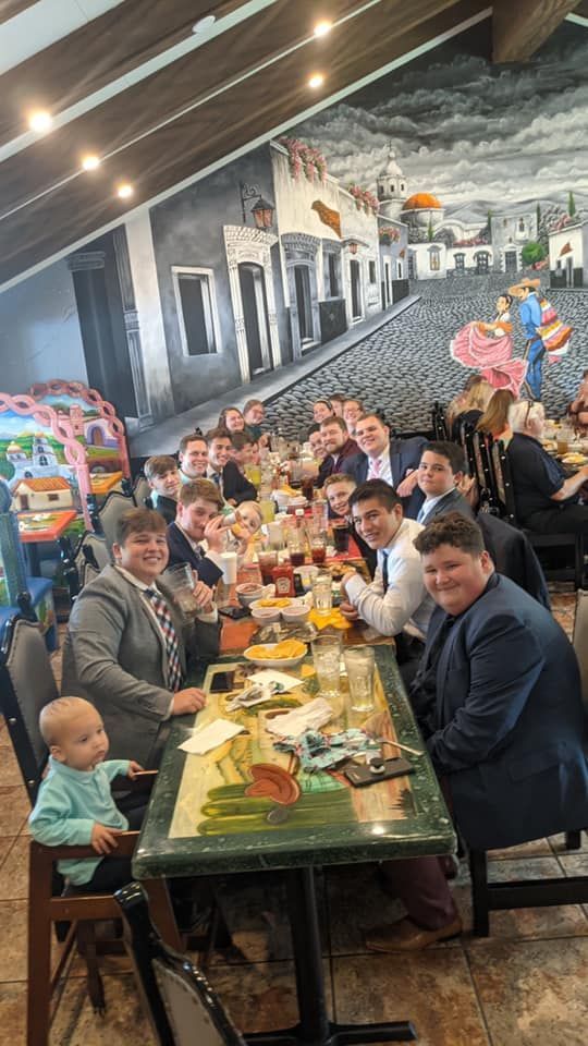 Group of people seated at a long table in a Mexican restaurant, celebrating, child in a high chair in the foreground.
