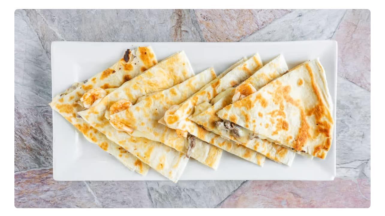Quesadillas on a white rectangular plate, cut into triangles.