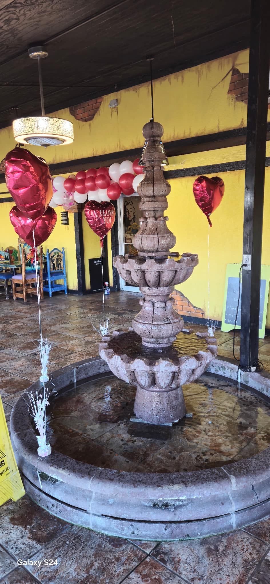 A stone fountain with heart-shaped balloons indoors, likely at a restaurant.