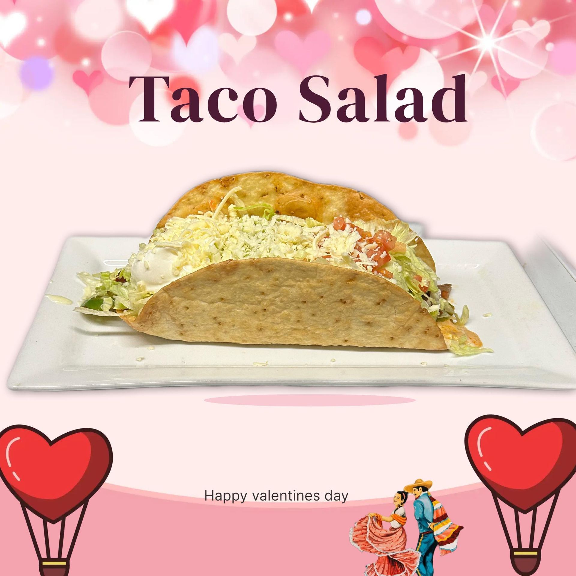 Taco salad in a crispy shell on a white plate, with pink hearts and balloons. 