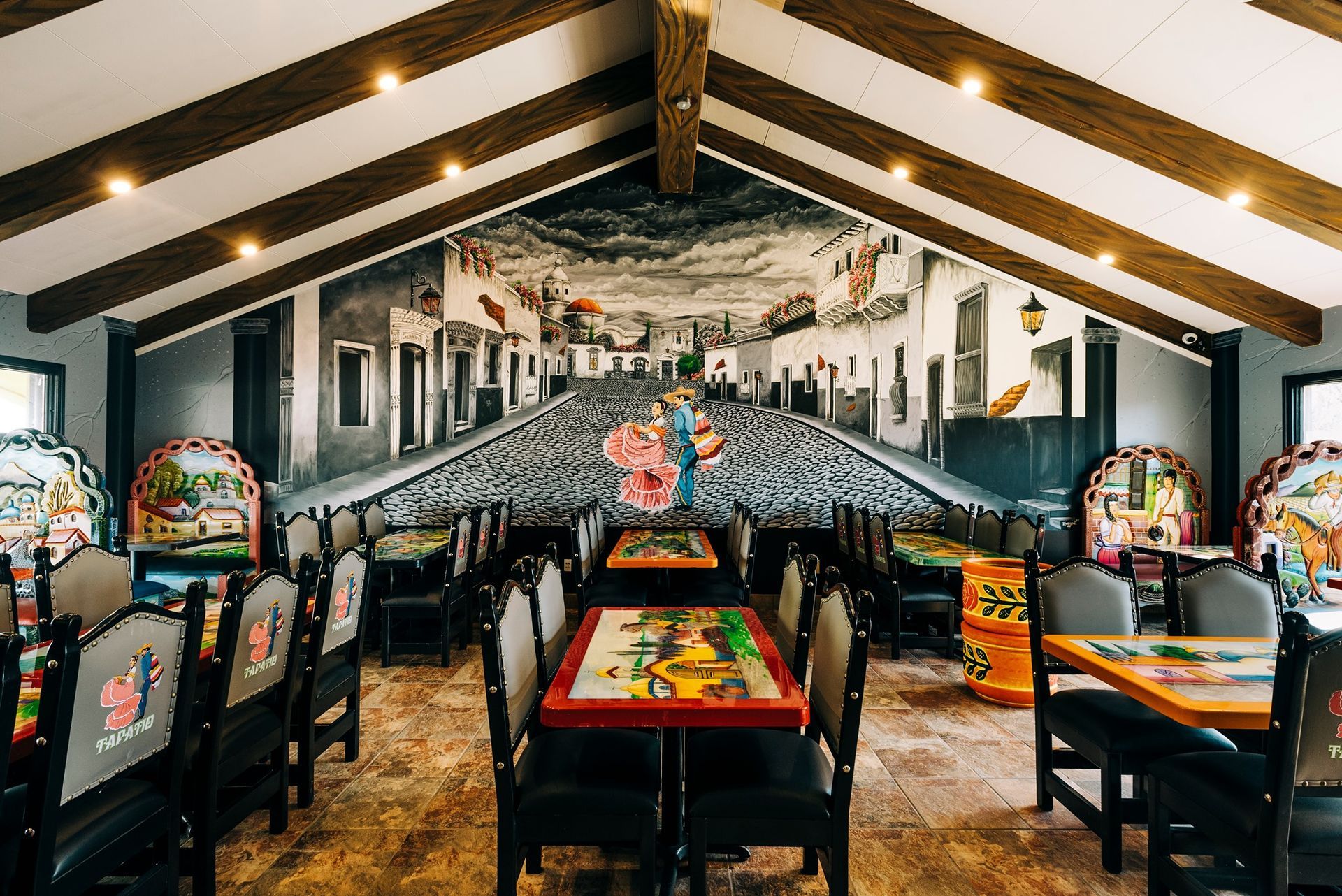Restaurant interior with tables, chairs, and a mural depicting a cobblestone street.