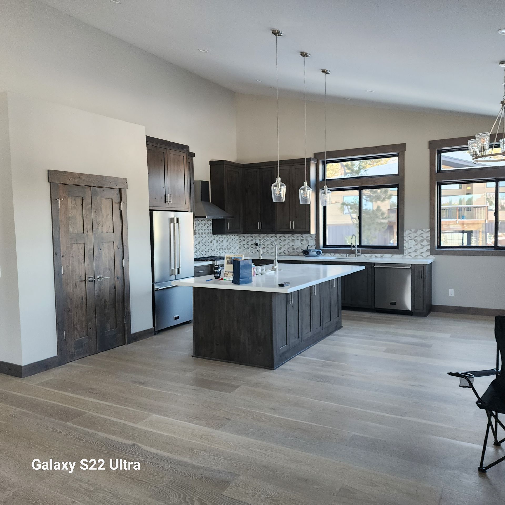 Modern kitchen with dark wood cabinets, white island, stainless fridge, and light hardwood floors