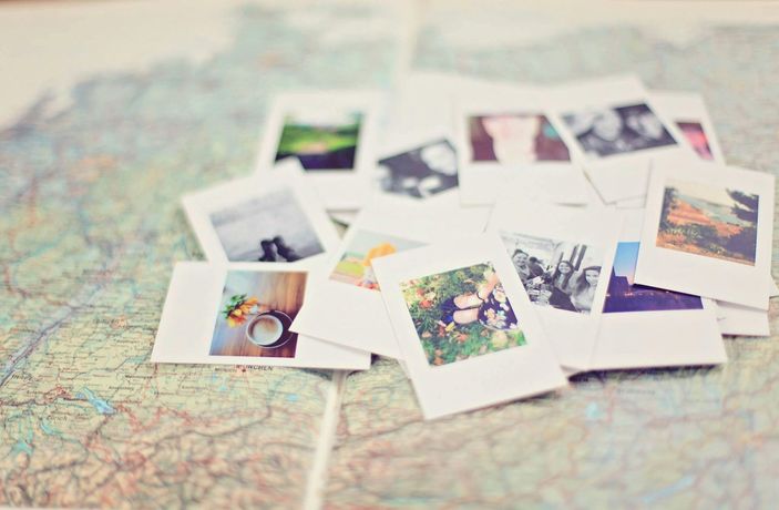 Pile of polaroid photos scattered on a detailed map, capturing travel memories.