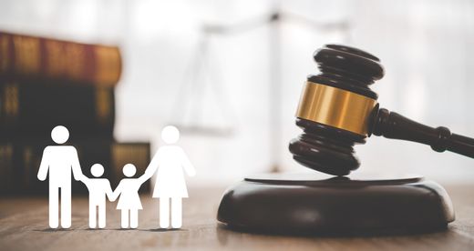 A family is standing next to a judge 's gavel on a wooden table.