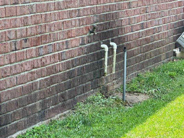 A brick wall with a couple of pipes coming out of it.