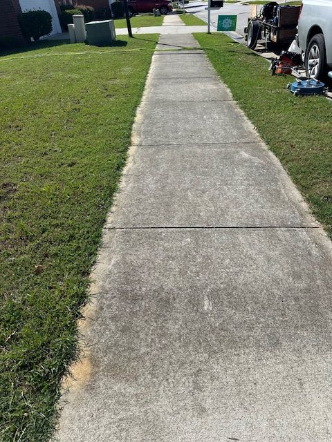 A sidewalk with grass on the side of it and a truck parked on the side of it.