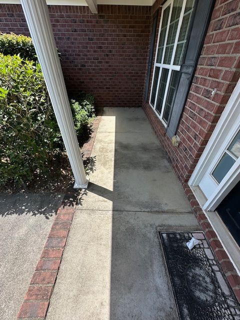 A brick house with a concrete walkway leading to the front door.