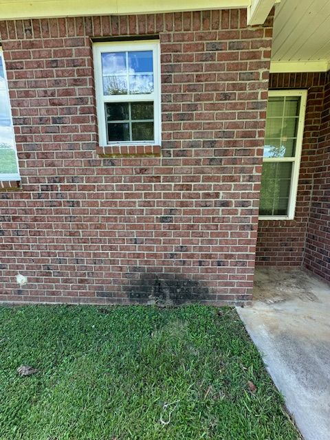 A brick house with a window and a concrete walkway.