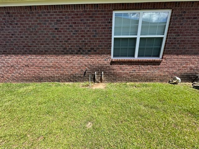 A brick house with a window and a lawn in front of it.