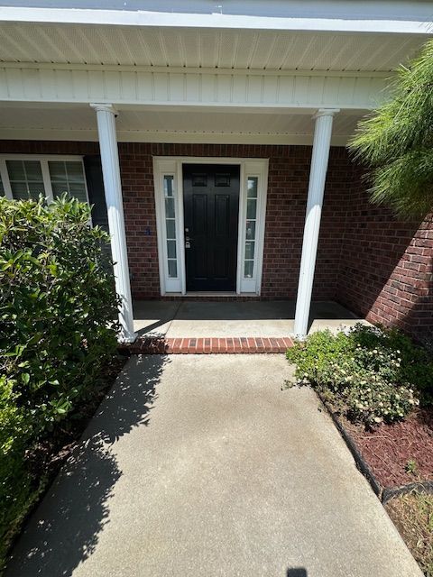 A brick house with a black door and a white porch
