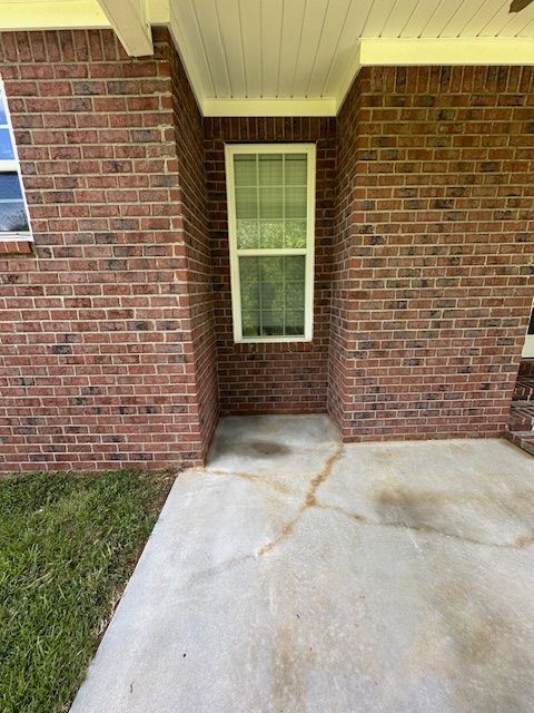 A brick house with a window and a concrete walkway.