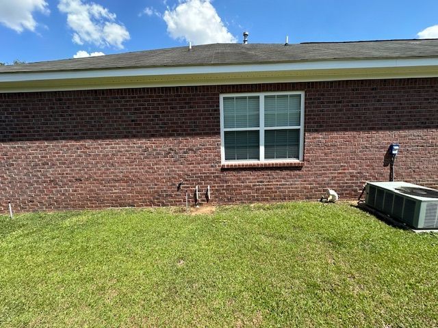 A brick house with a large window and a lawn in front of it.