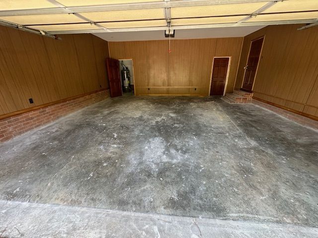 An empty garage with a concrete floor and wooden walls.