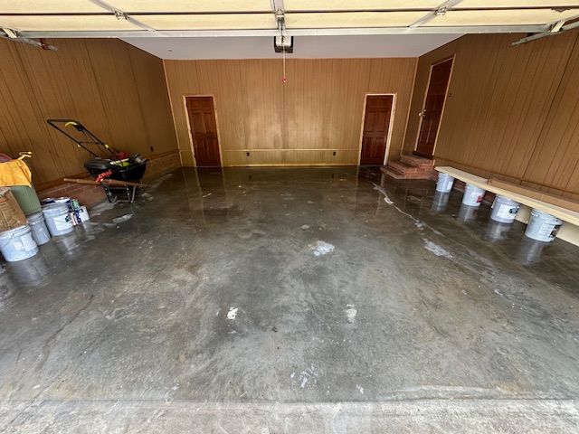 An empty garage with buckets and a bench in it.