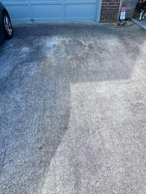 A car is parked in a driveway next to a garage door.