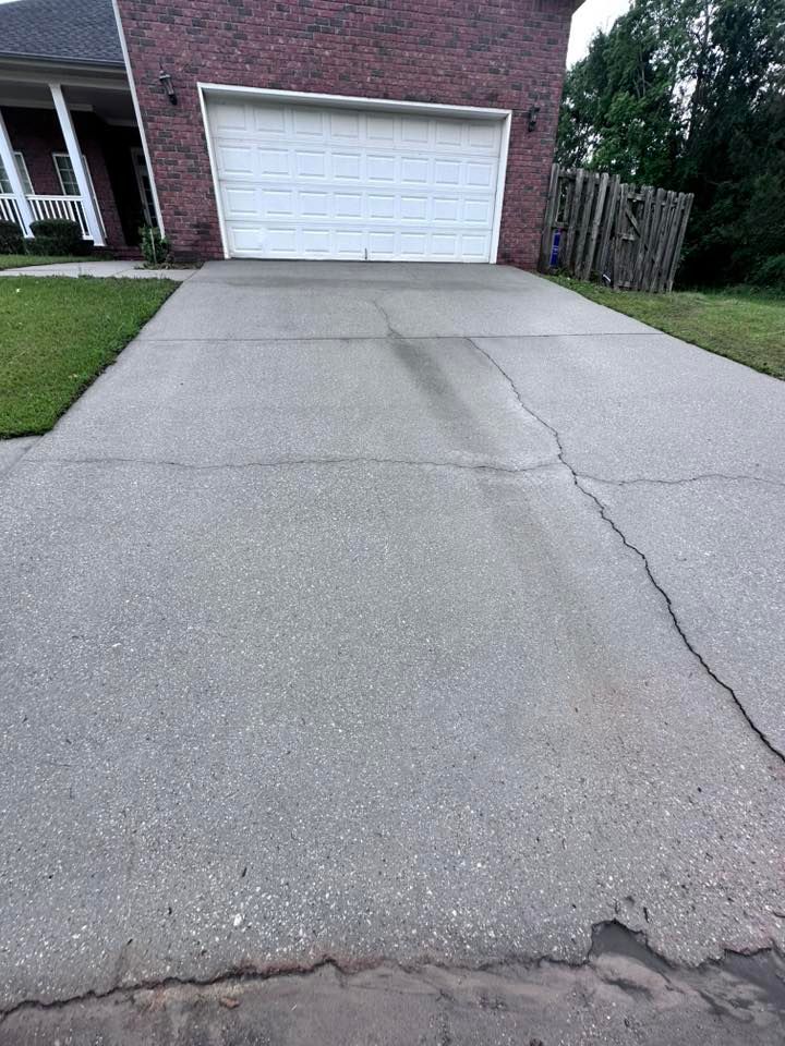 A brick house with a white garage door and a concrete driveway in front of it.