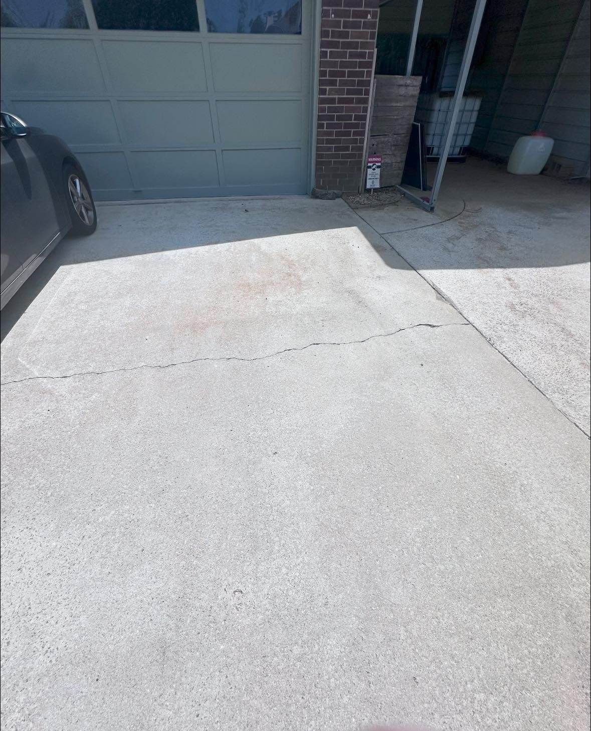 A car is parked in a driveway next to a garage door.