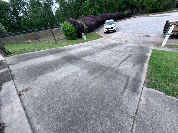 A white car is parked on the side of a concrete driveway.