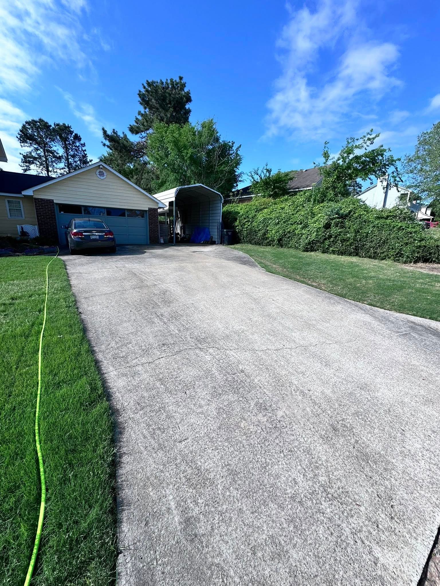 A driveway leading to a house with a car parked in the driveway.