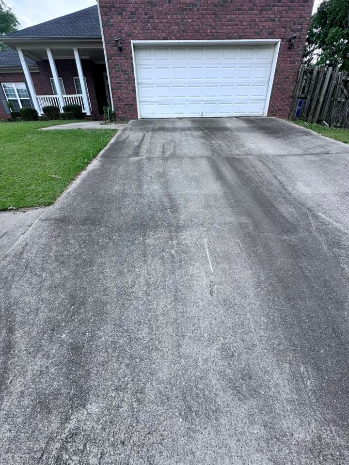 A dirty driveway in front of a brick house with a white garage door.