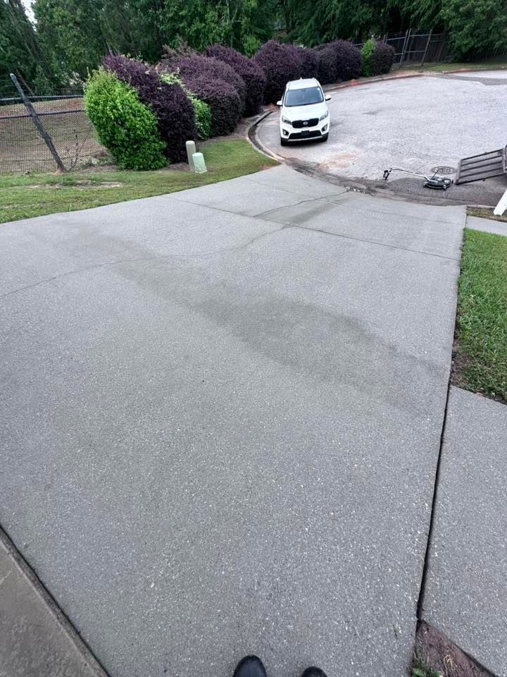 A white car is parked on the side of a concrete driveway.