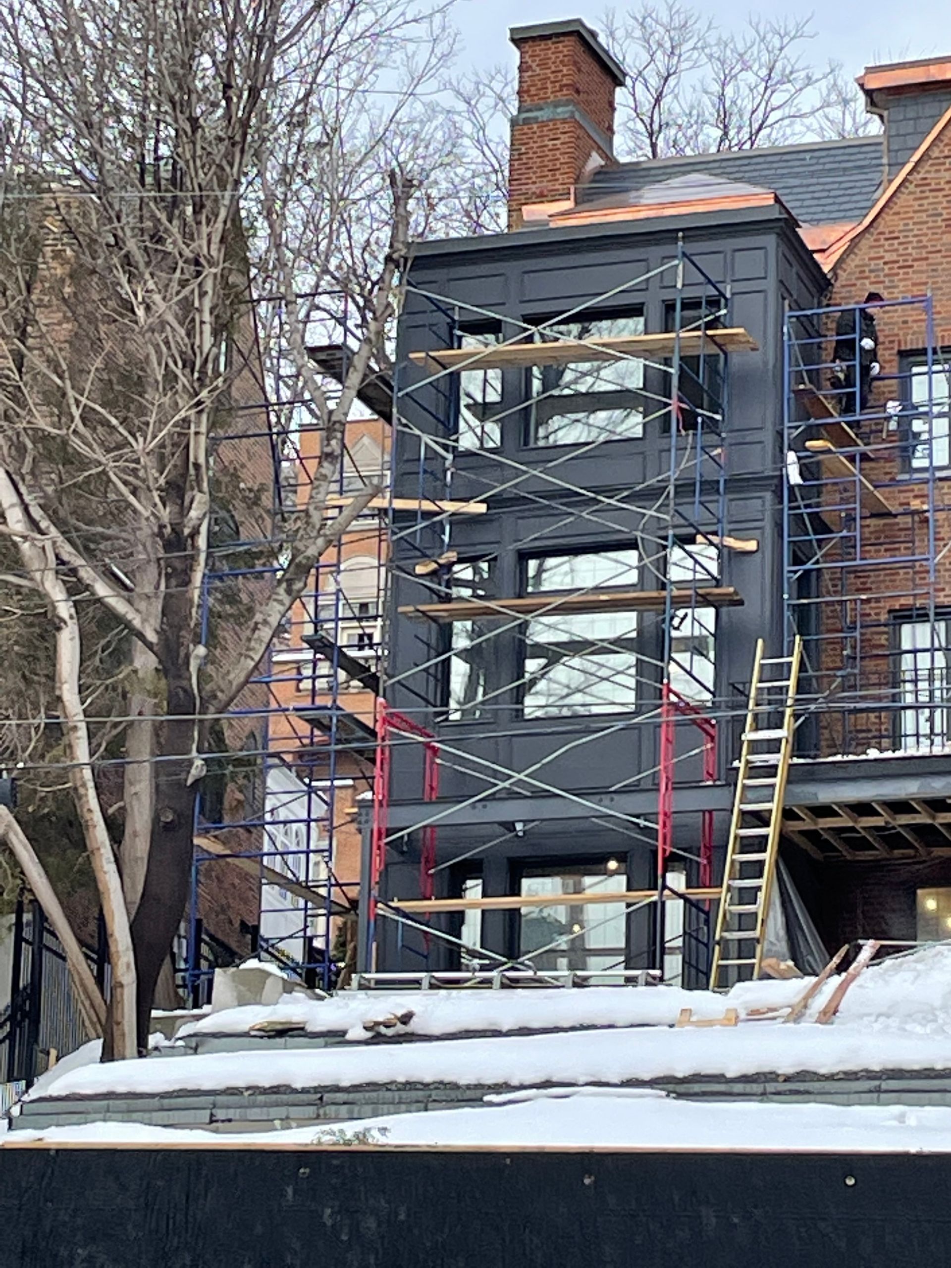 Un bâtiment en construction avec des échafaudages autour et de la neige au sol.