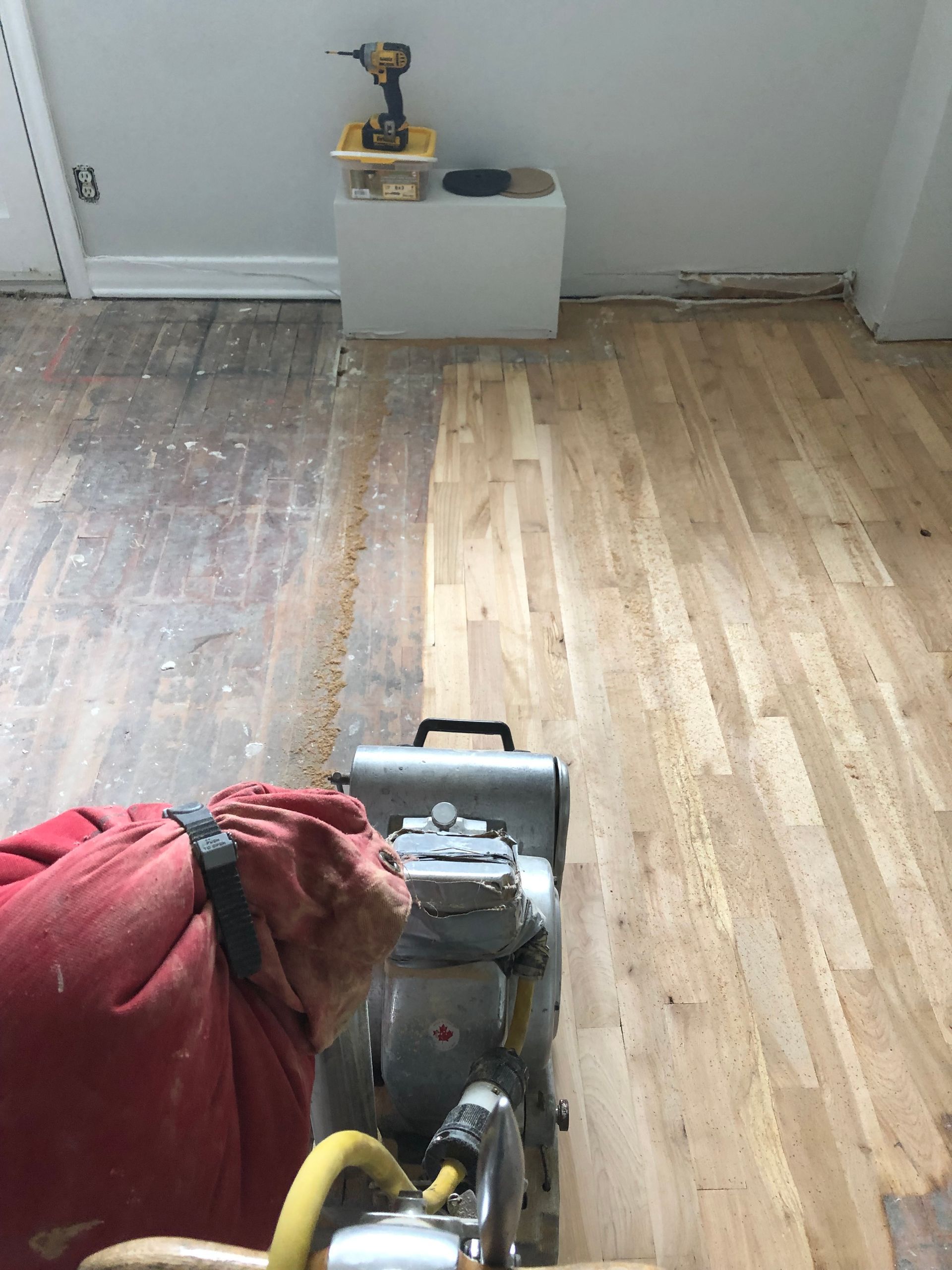 Une personne ponce un plancher en bois avec une machine.