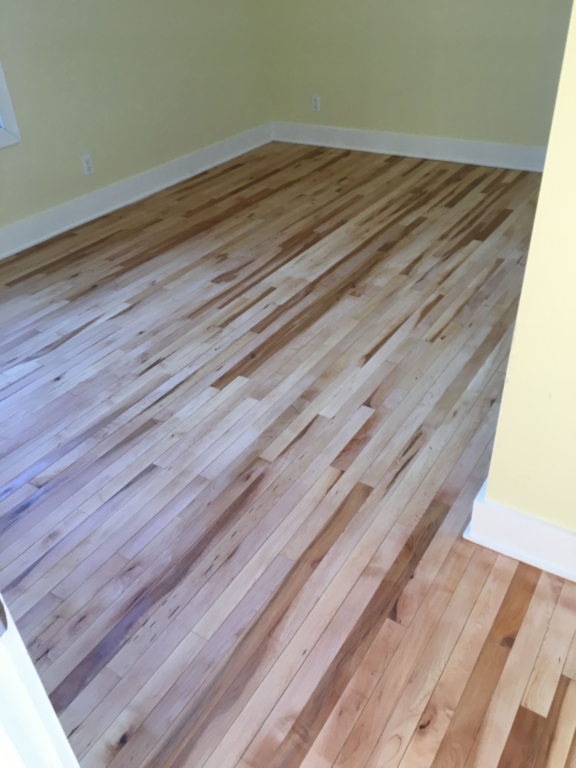 Une pièce avec du parquet et des murs jaunes