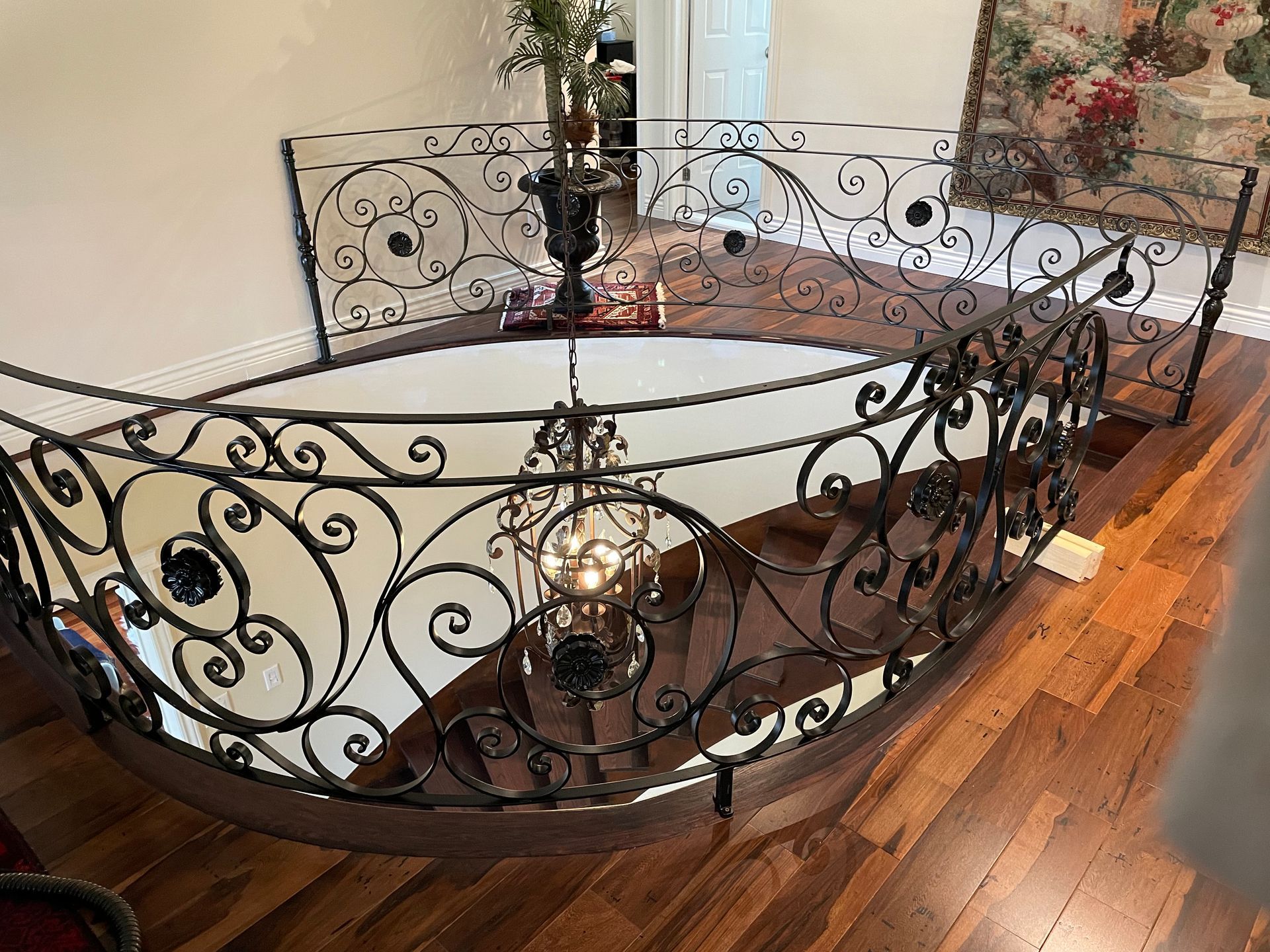 Une balustrade en fer forgé entoure un escalier en bois dans une maison.