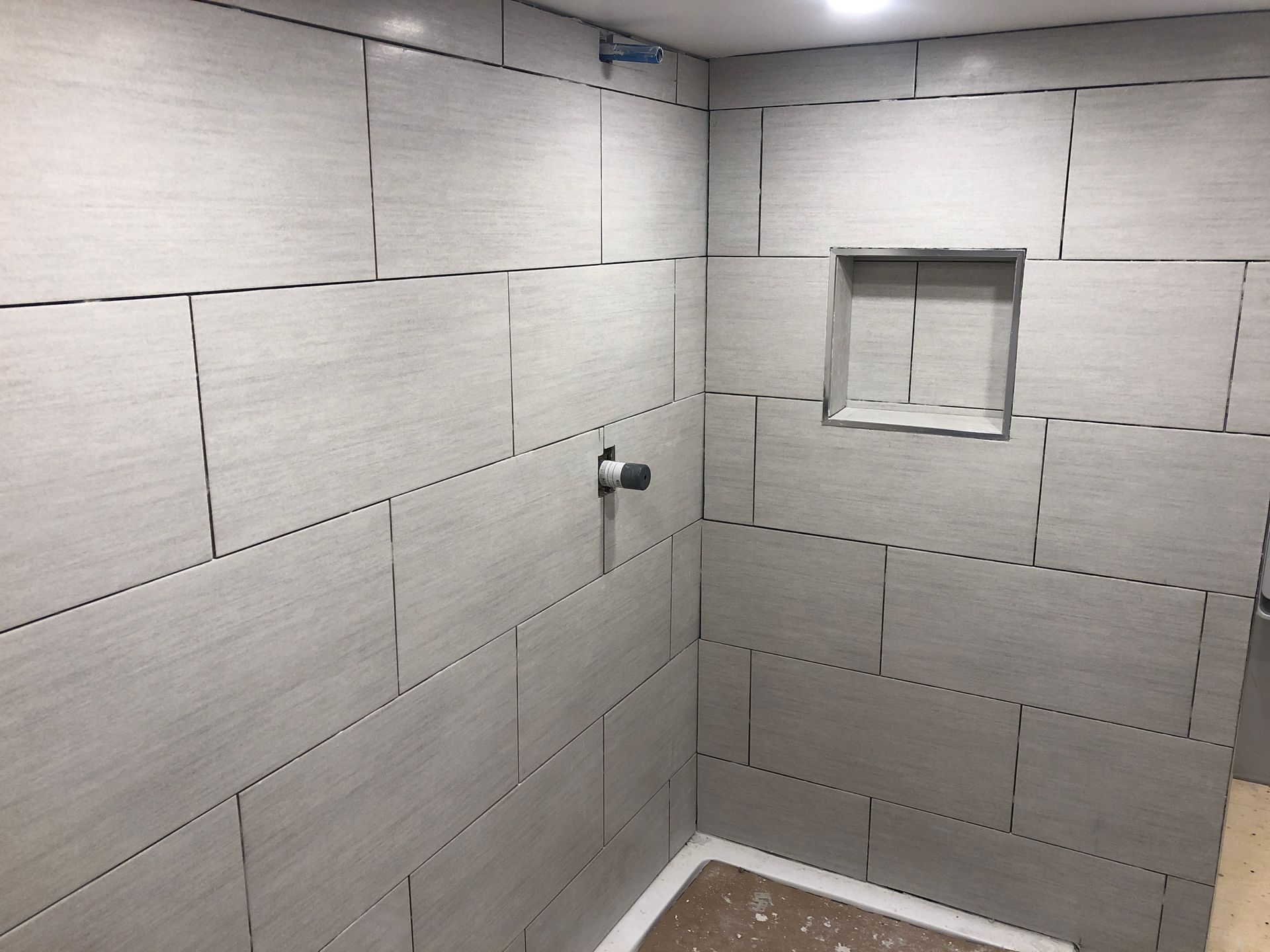 Une salle de bain avec carrelage blanc et pomme de douche