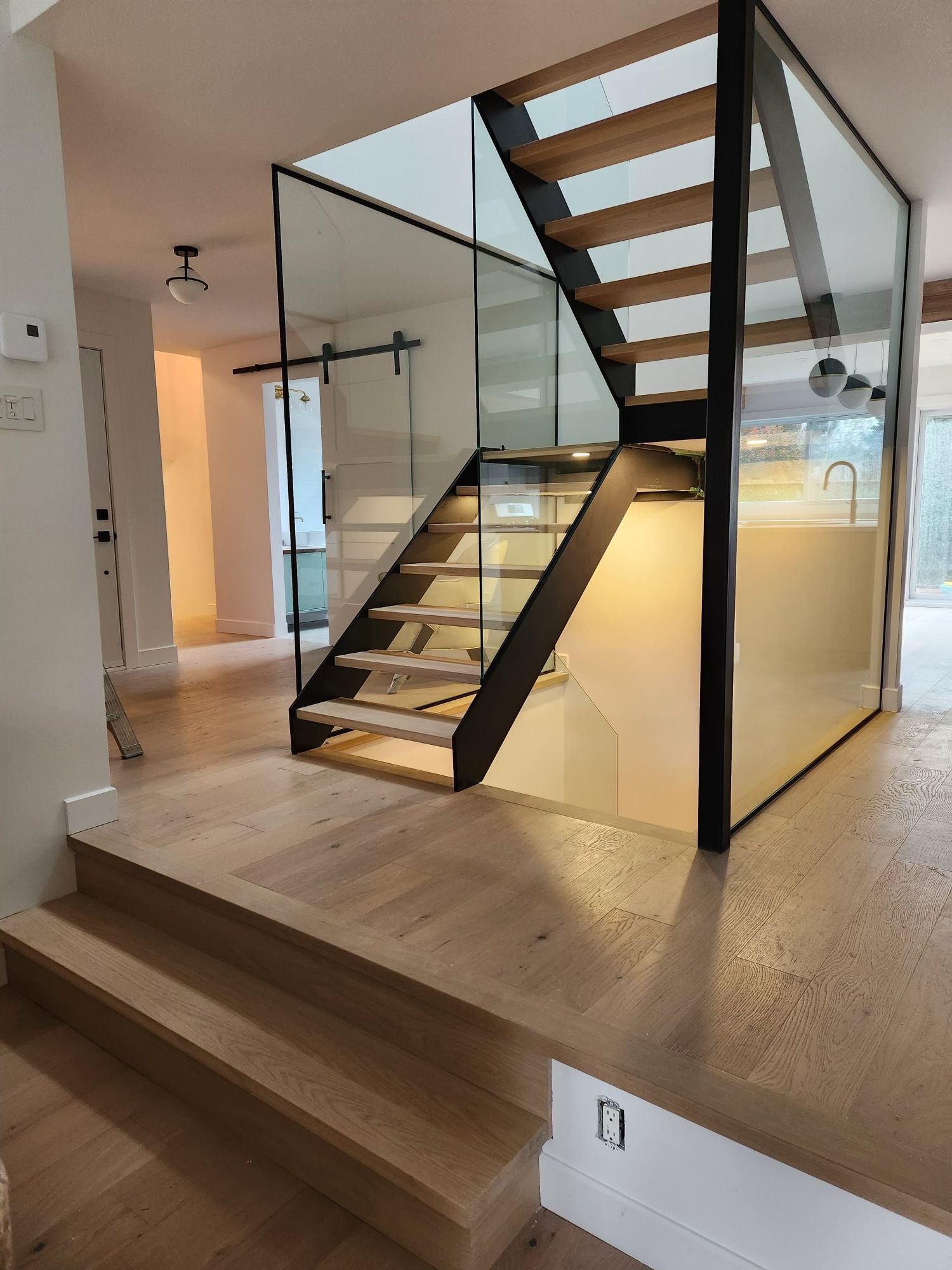 Un escalier en bois avec une rampe en verre dans une maison