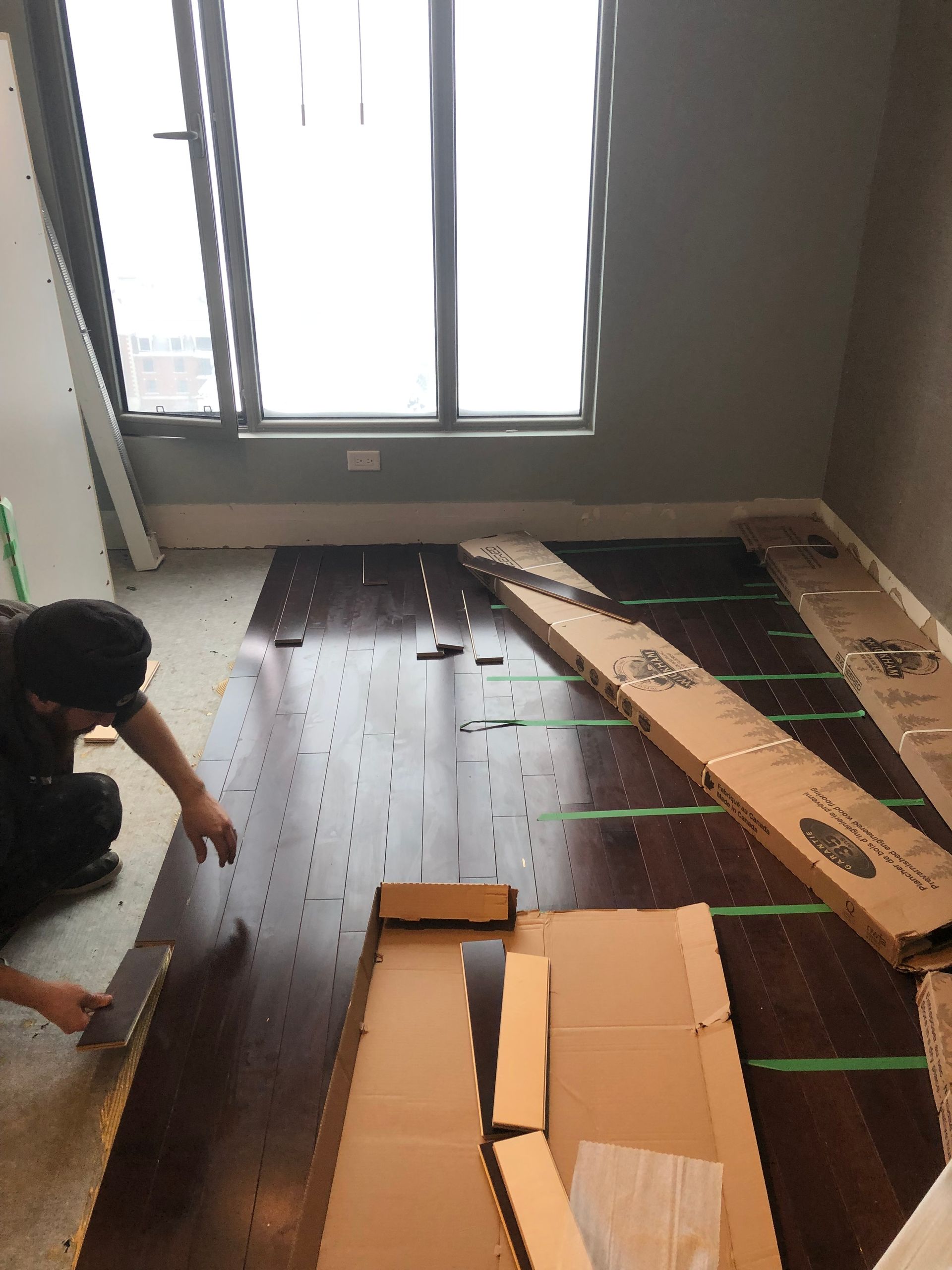 Un homme travaille sur un parquet dans une pièce