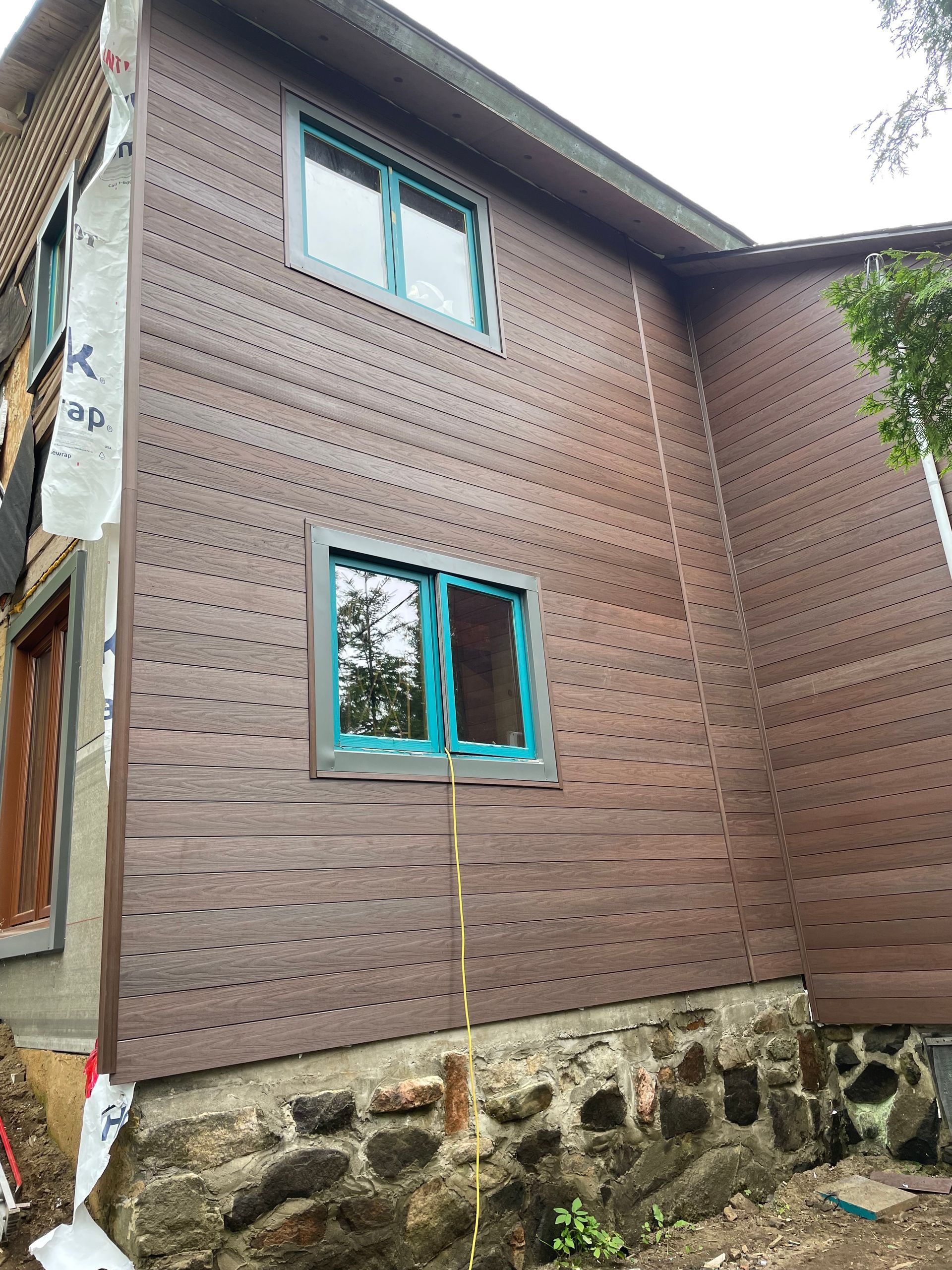 Une maison avec un bardage en bois et des fenêtres bleues est en construction.