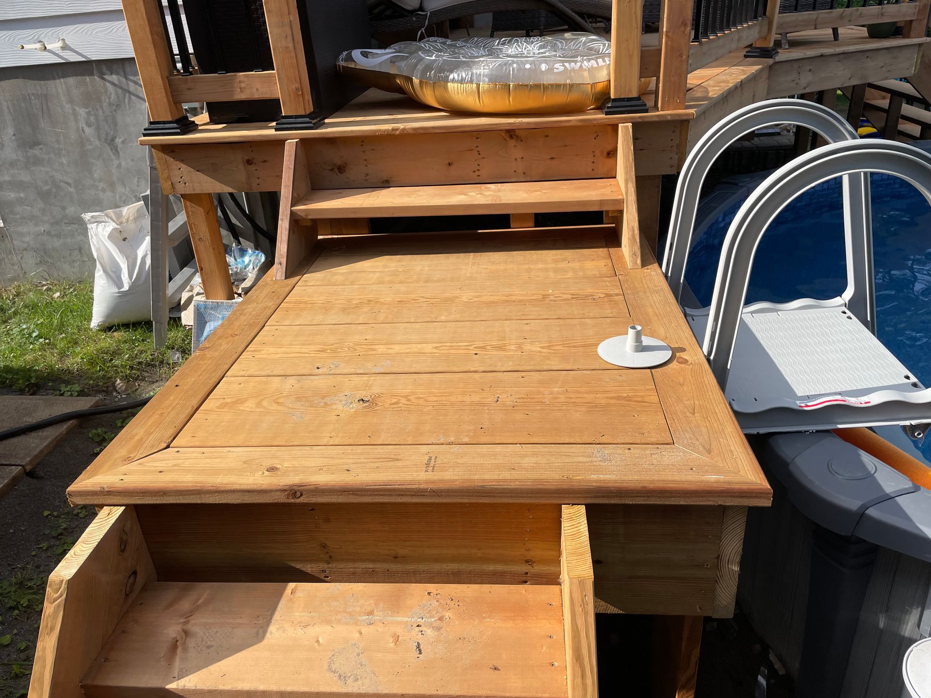Une terrasse en bois avec escalier menant à une piscine