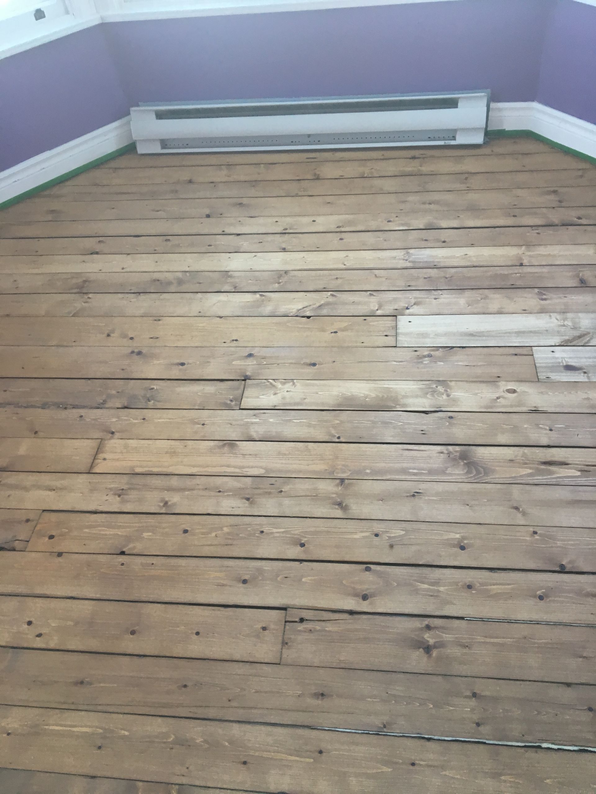 Une pièce vide avec un parquet et des murs violets.