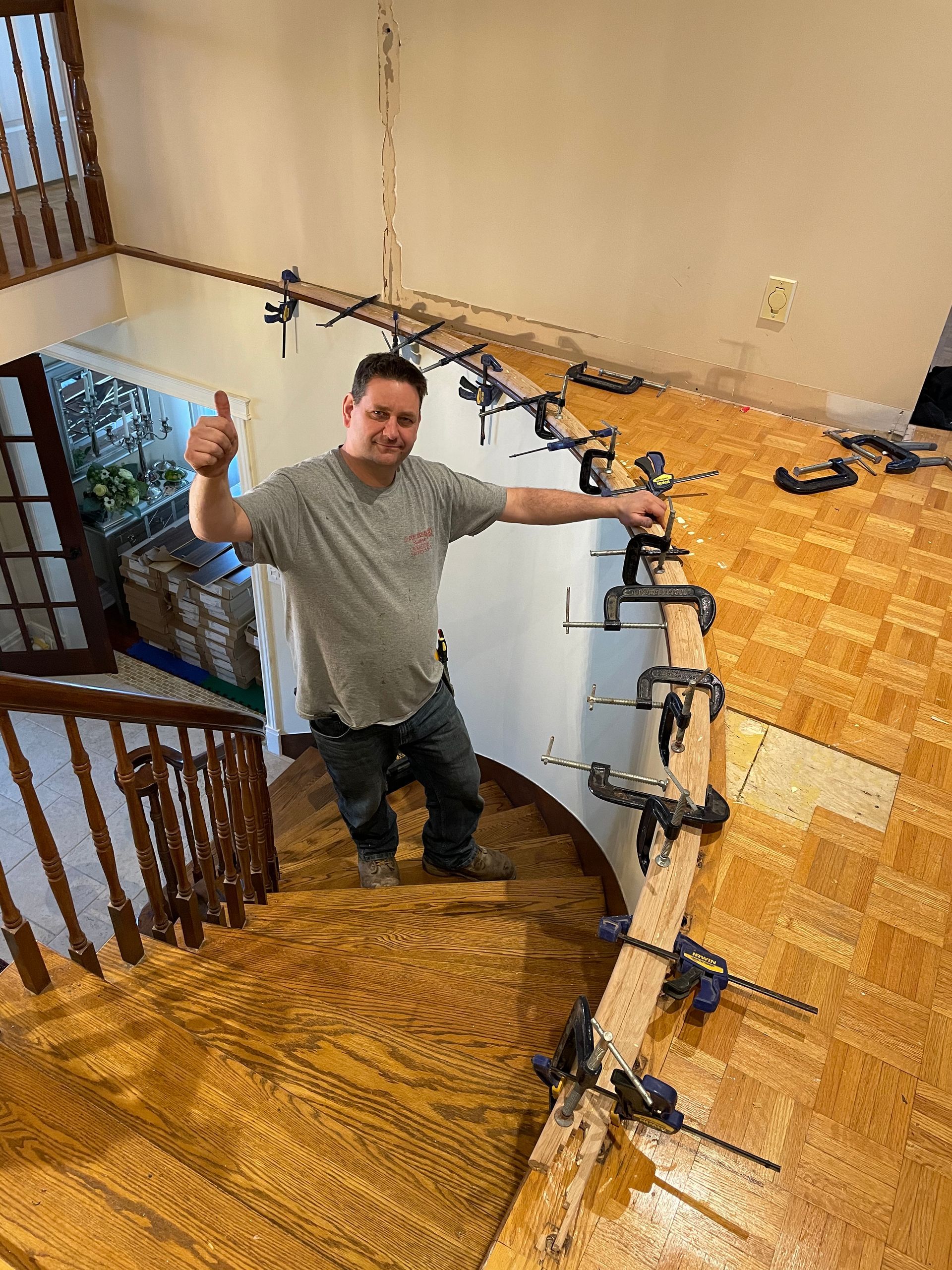 Un homme se tient au sommet d'un escalier en bois et lève le pouce.