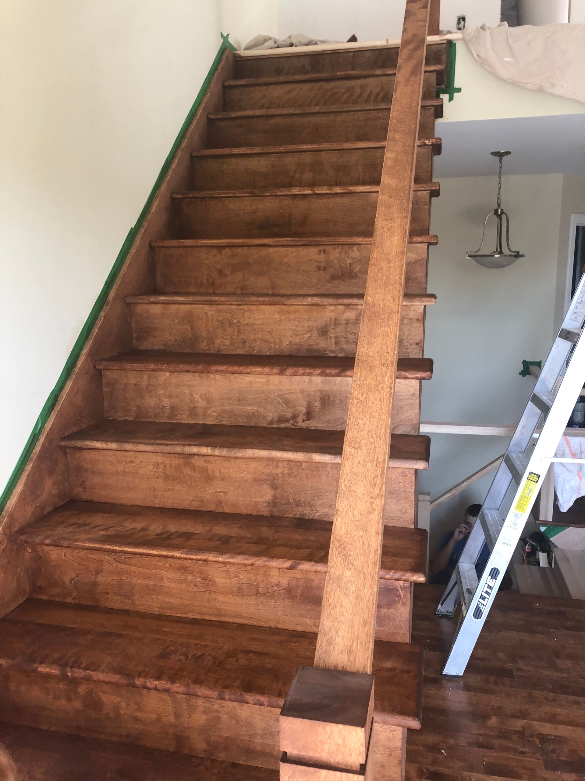Un escalier en bois est en cours de peinture dans une pièce avec une échelle.