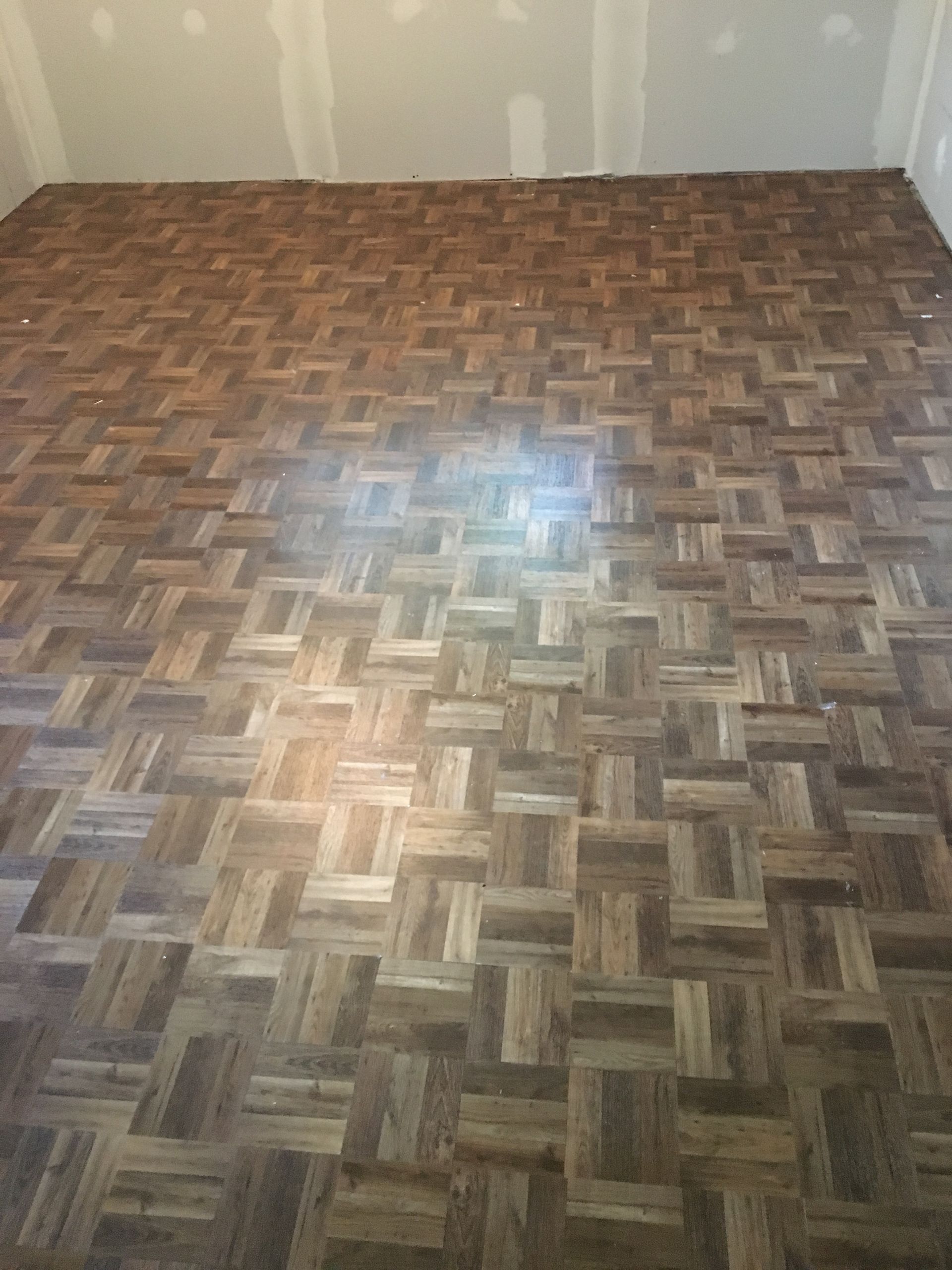 Une pièce avec du parquet et un mur blanc.