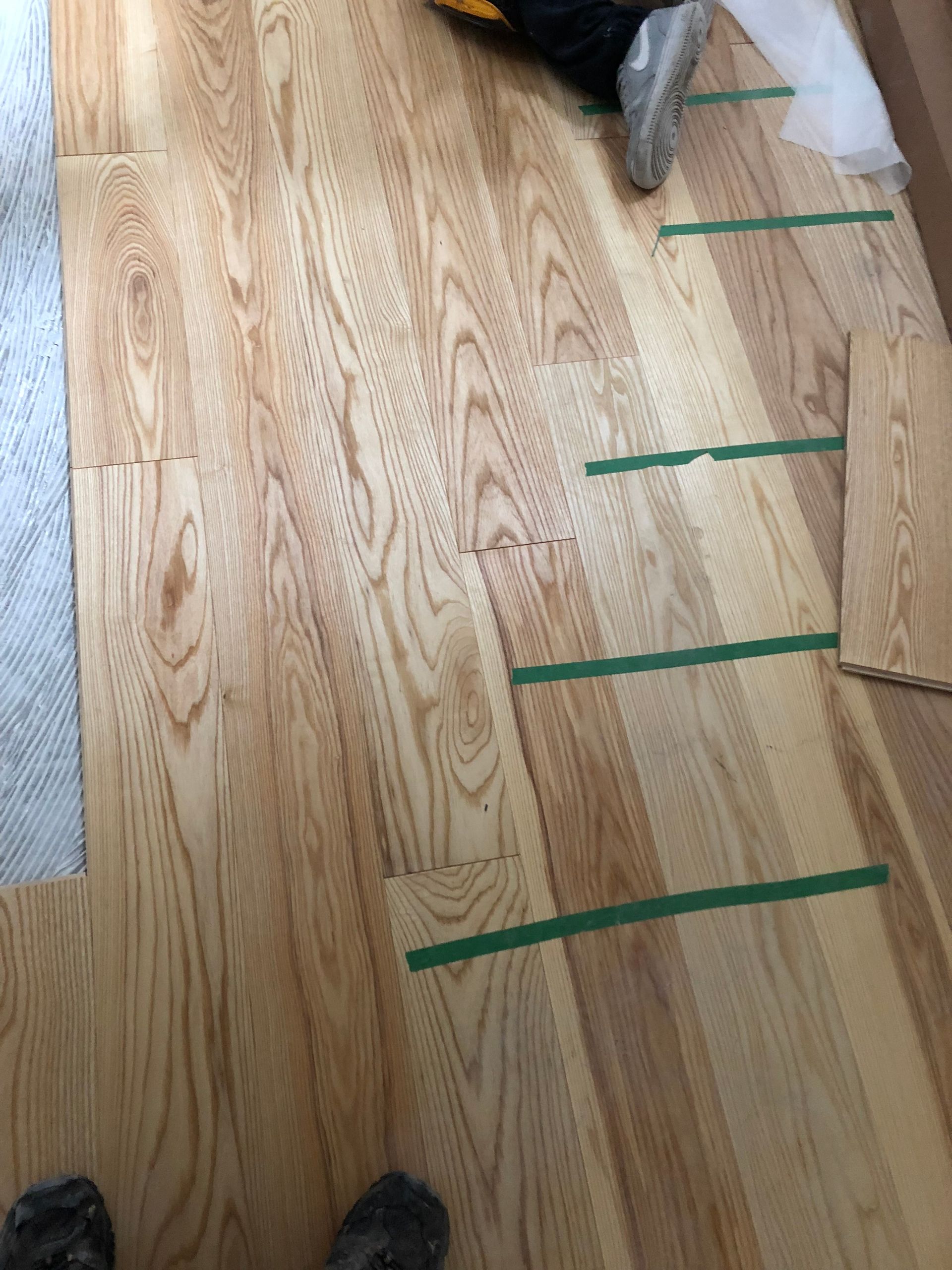 Une personne est allongée sur un plancher en bois avec du ruban adhésif vert dessus.