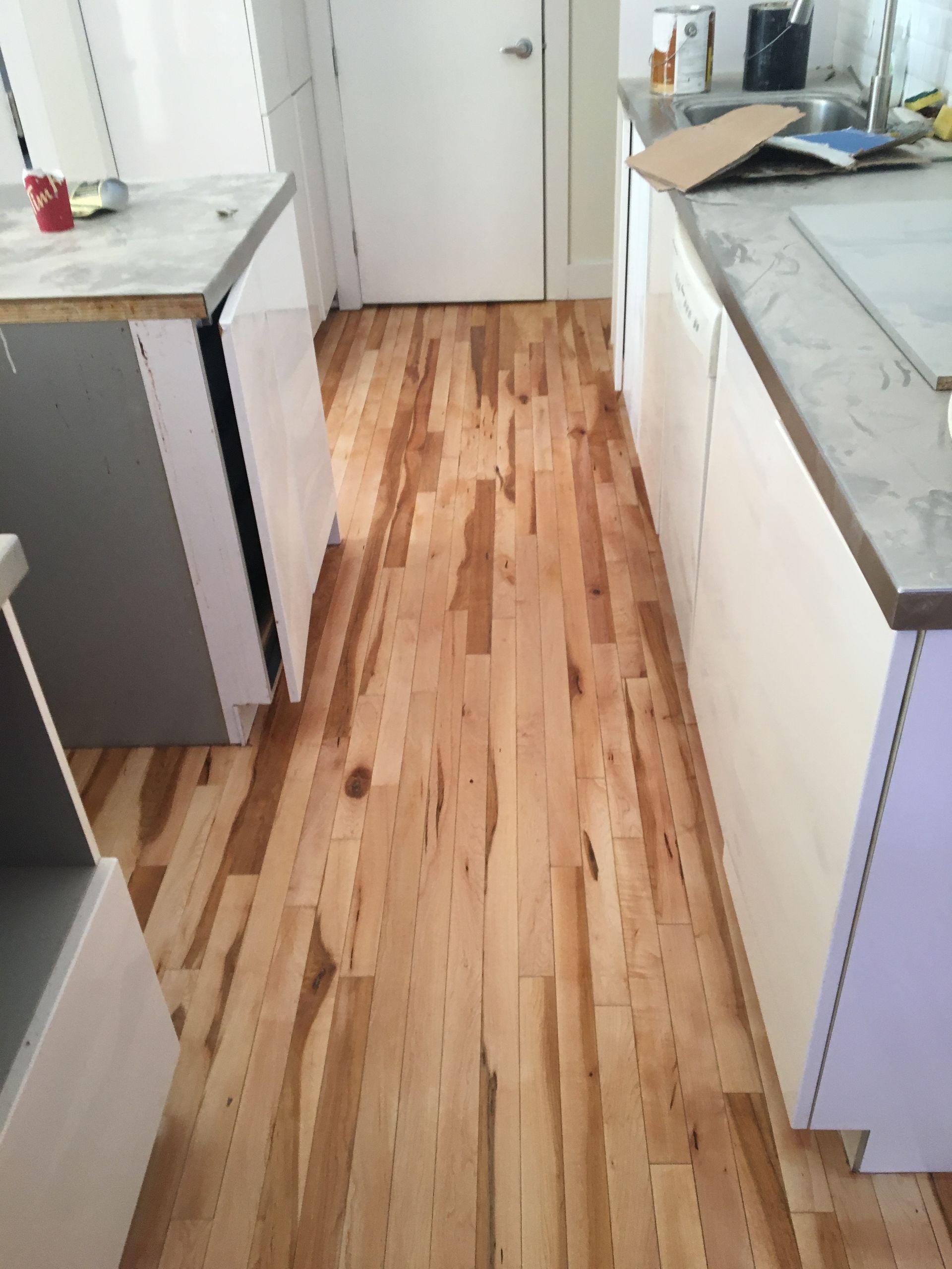 Une cuisine avec planchers de bois franc et armoires blanches