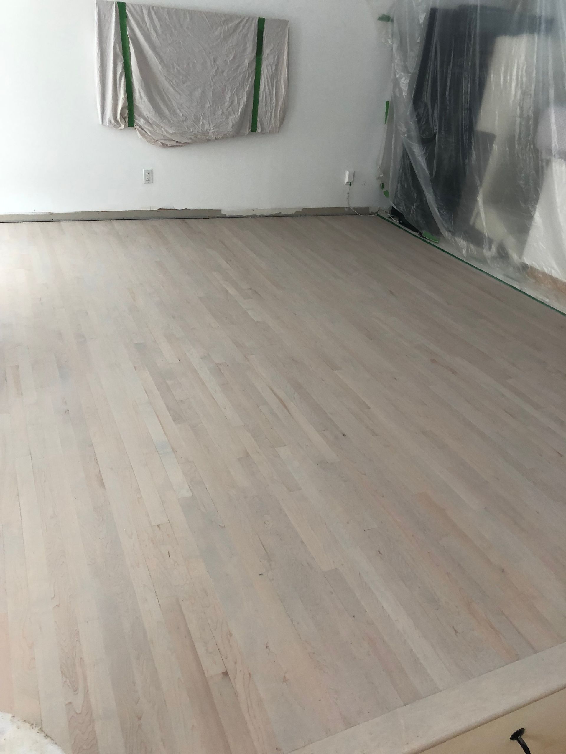 Une grande pièce vide avec un parquet et des murs blancs.