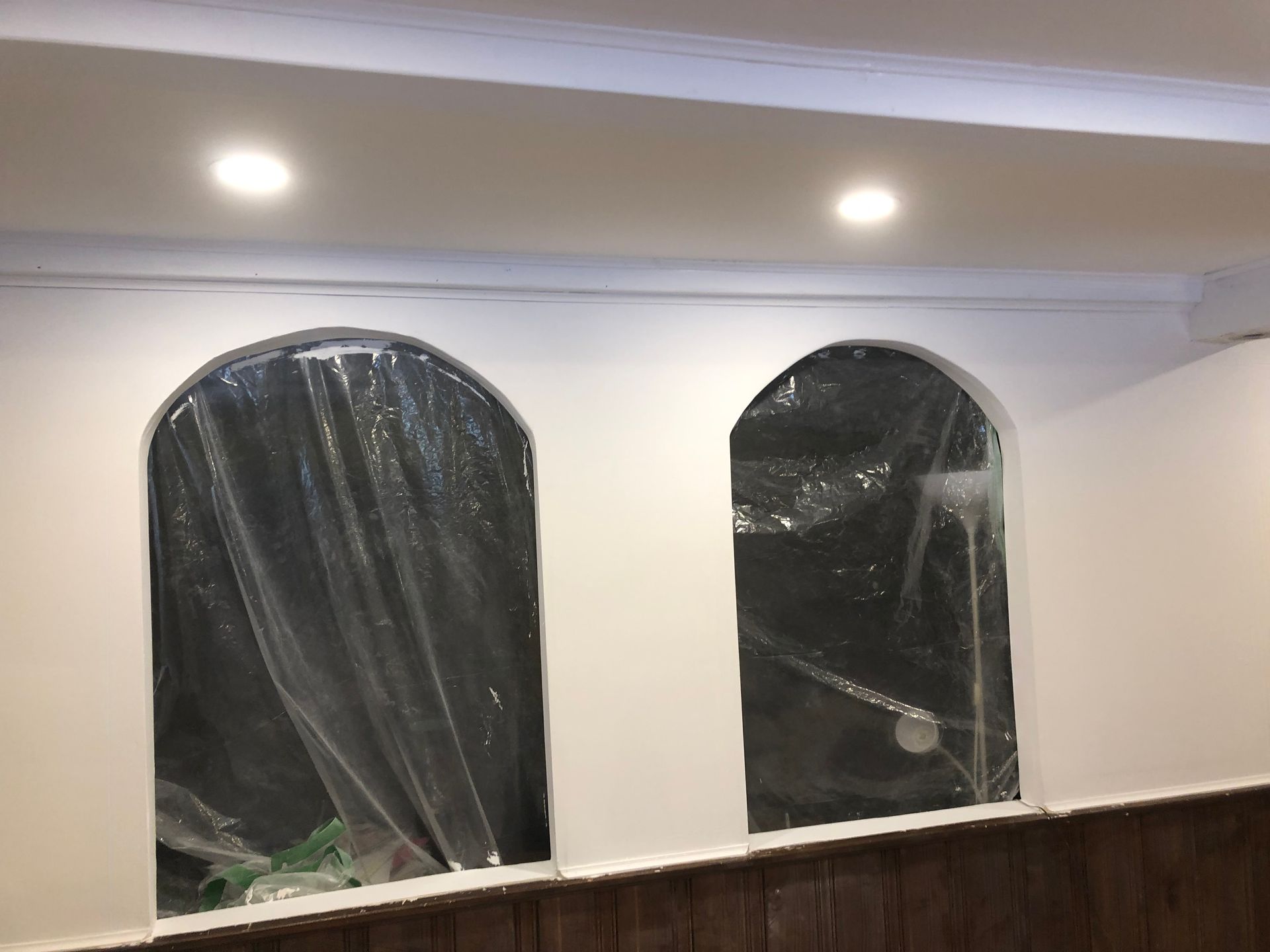 Une pièce avec deux fenêtres cintrées et un mur en bois.