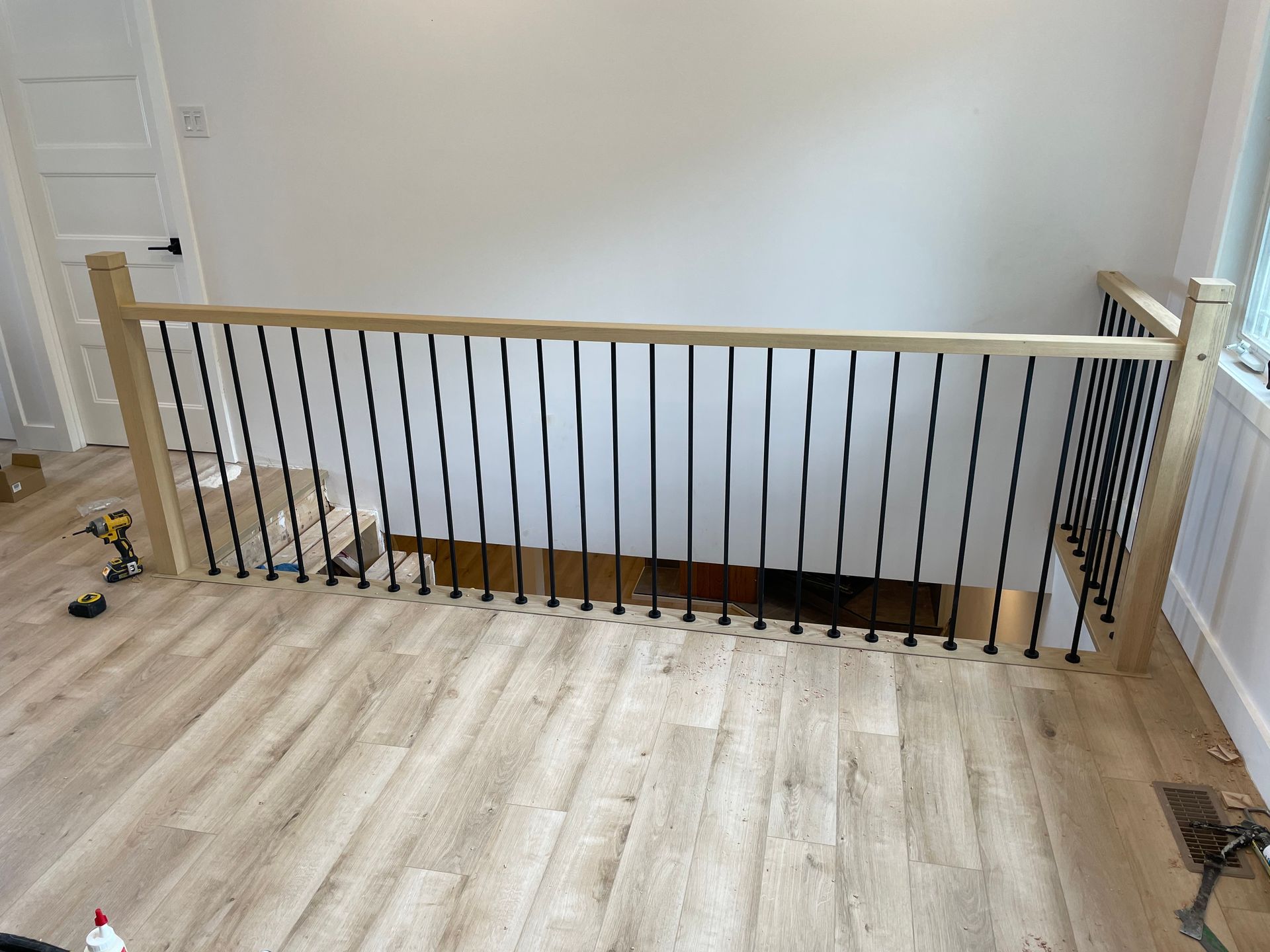 Un escalier en bois avec une rampe noire est en cours de construction dans une maison.