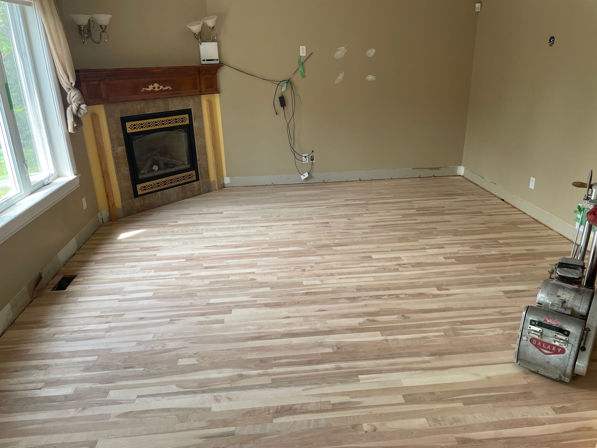 Un salon avec parquet et cheminée.