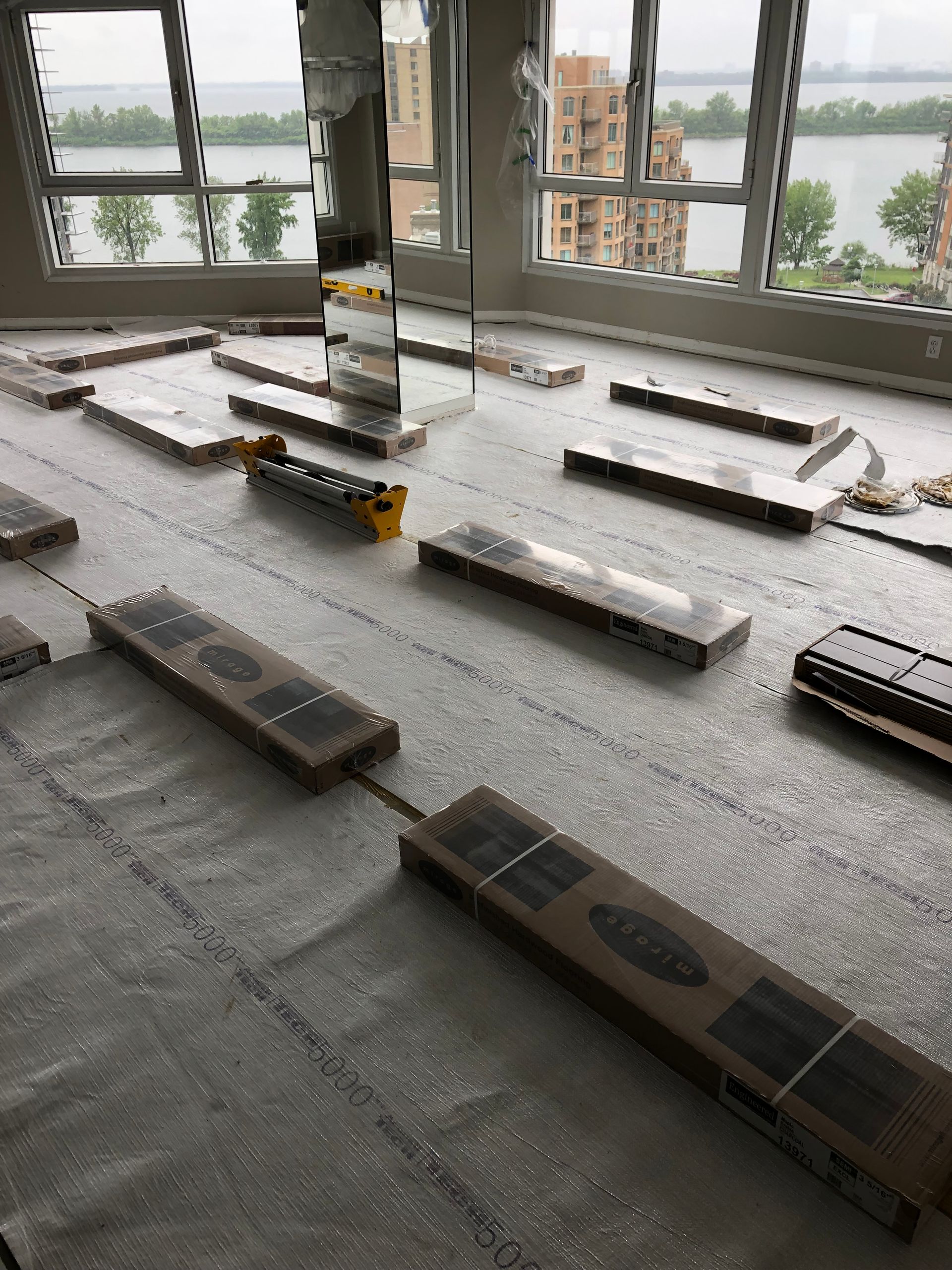 Une pièce avec beaucoup de cartons au sol et beaucoup de fenêtres.