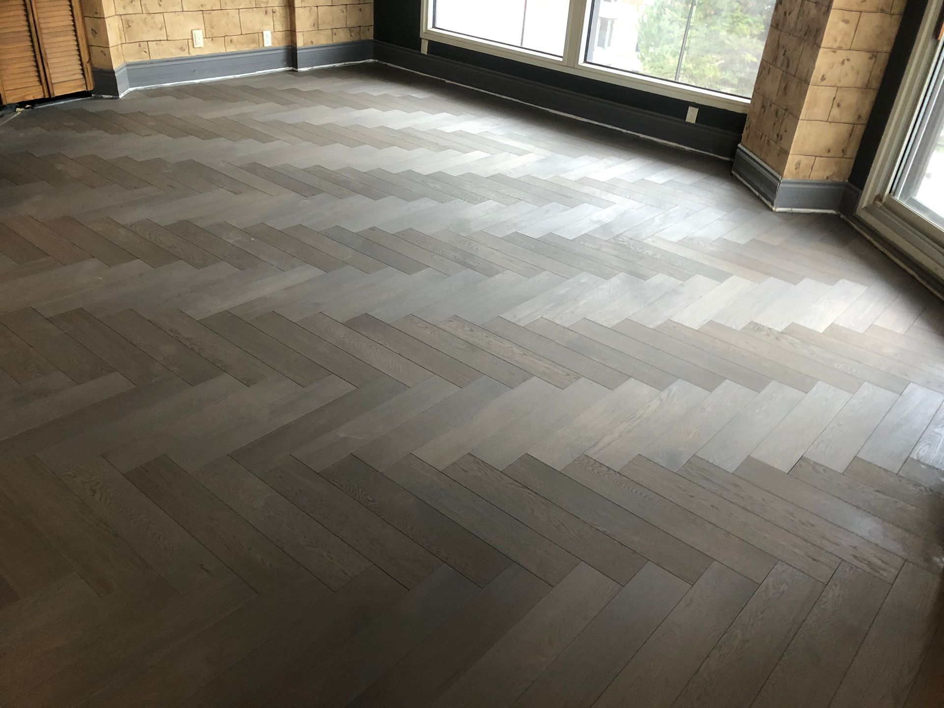 Une pièce avec un parquet en bois et un motif à chevrons