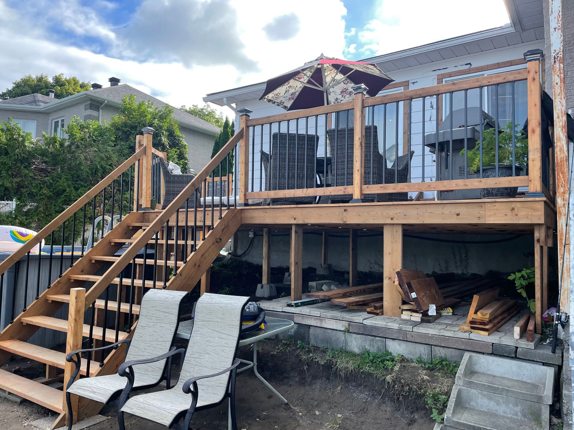Une terrasse en bois avec escaliers et chaises devant une maison.