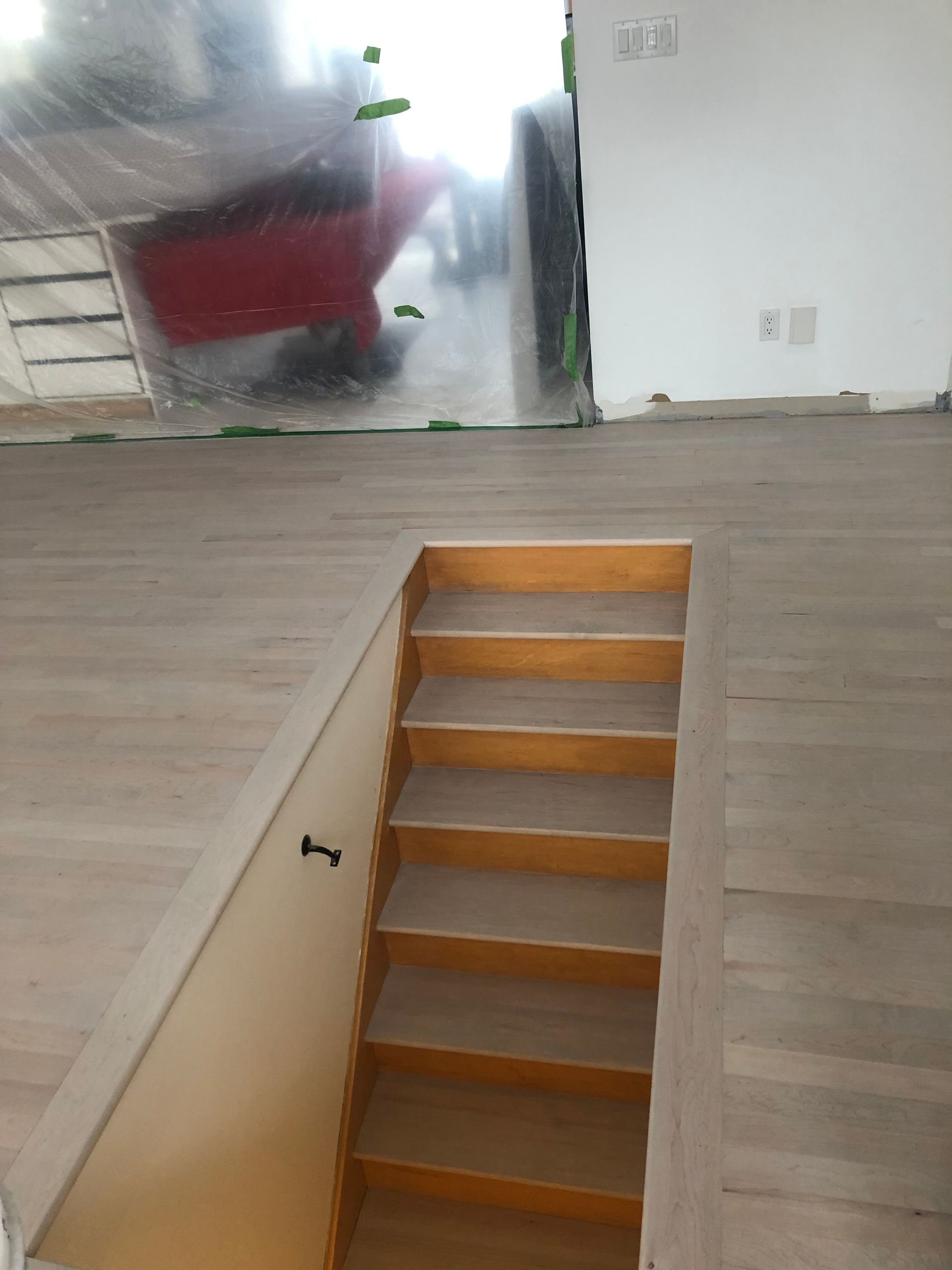 Un escalier en bois dans une pièce avec une brouette en arrière-plan.